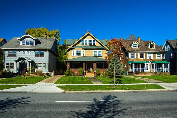 Three classic homes on a tree-lined residential street representing the communities FHJ Properties serves
